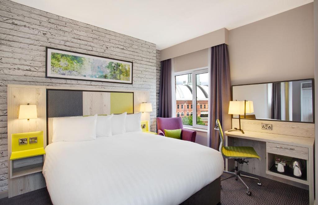 ein Hotelzimmer mit einem großen Bett und einem Schreibtisch in der Unterkunft Leonardo Hotel Manchester Central in Manchester