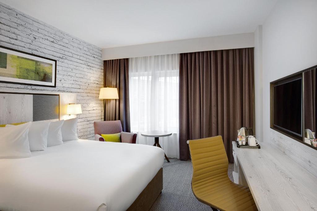 a hotel room with a large bed and a television at Leonardo Hotel Manchester Central in Manchester