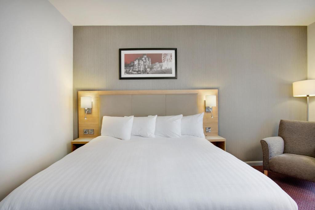 a bedroom with a large white bed and a chair at Leonardo Hotel Manchester Central in Manchester
