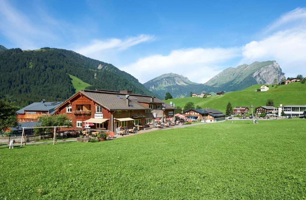 un village avec un champ verdoyant et des montagnes en arrière-plan dans l'établissement Schrannenhof, à Schoppernau