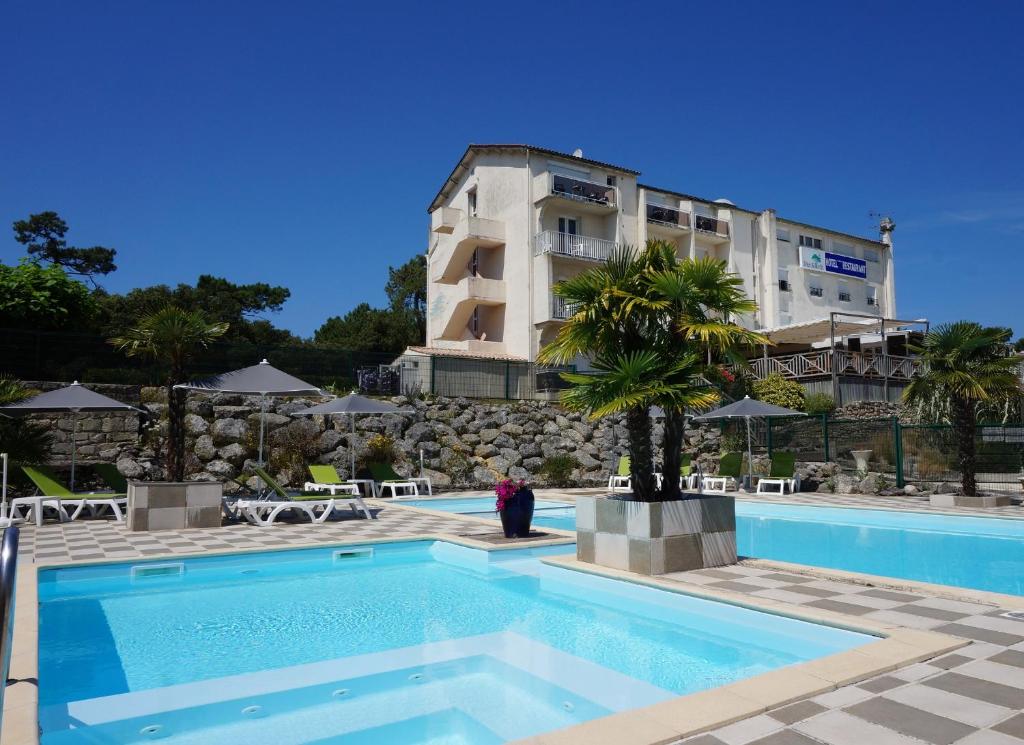 un hôtel avec une piscine en face d'un bâtiment dans l'établissement Hôtel Mer et Forêt, à Saint-Trojan-les-Bains