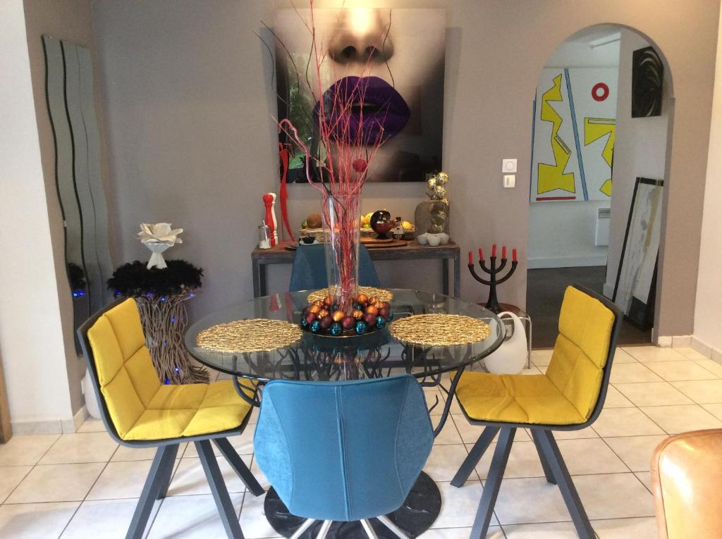 a dining room with a glass table and yellow chairs at La Parenthèse in Montluçon