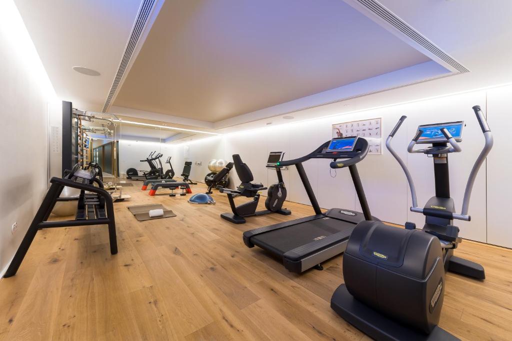 A compact, well-equipped fitness room with cardio machines, weights, and mirrored walls.