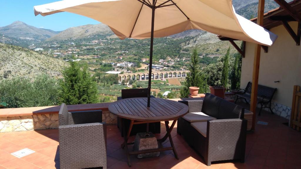 un patio con mesa, sillas y sombrilla en Casa degli Ulivi, en Gaeta