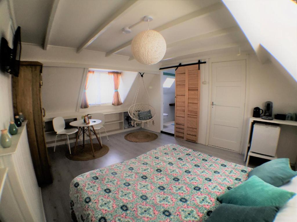 ein Schlafzimmer mit einem Bett, einem Tisch und einem Stuhl in der Unterkunft B&B Little Miss Sunshine in Zandvoort