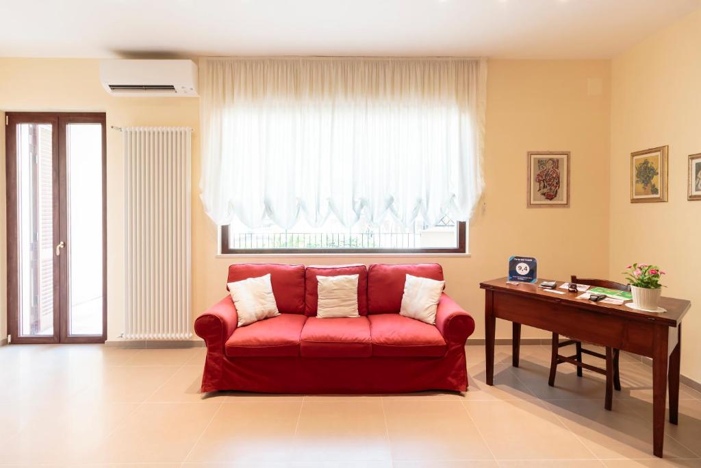 un divano rosso in un soggiorno con finestra di Corte dei Nobili a Conversano