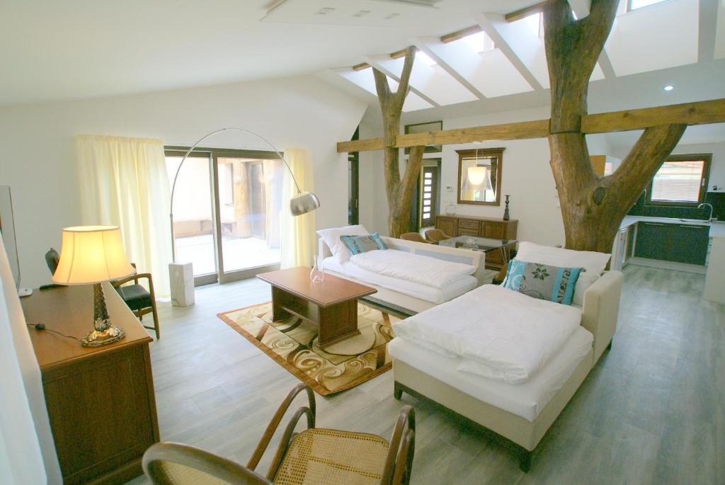 Elle comprend un salon doté d'un mobilier blanc et d'un arbre. dans l'établissement Golf Apartments, à Bernolákovo
