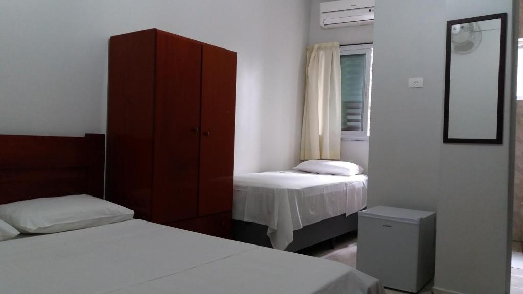 una camera con due letti, un armadio e uno specchio di Apeninos Suites Basicas a San Paolo
