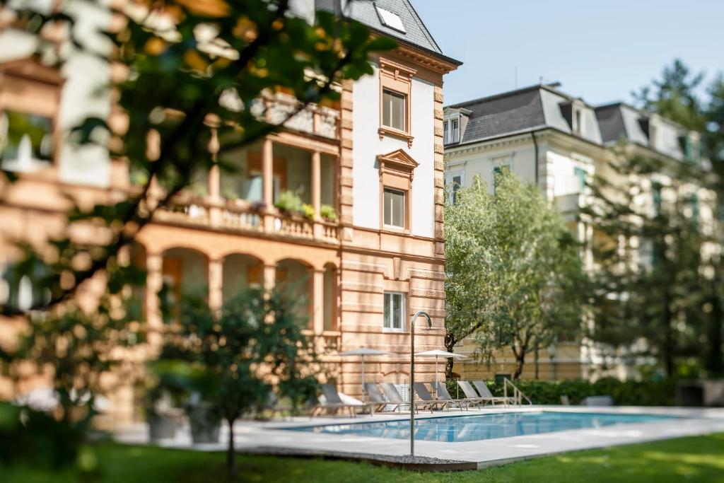 a large building with a swimming pool in front of it at Windsor Merano Hotel & Suites in Merano