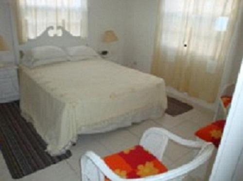 a bedroom with a white bed and two chairs at AnnJenn Apartments in Christ Church