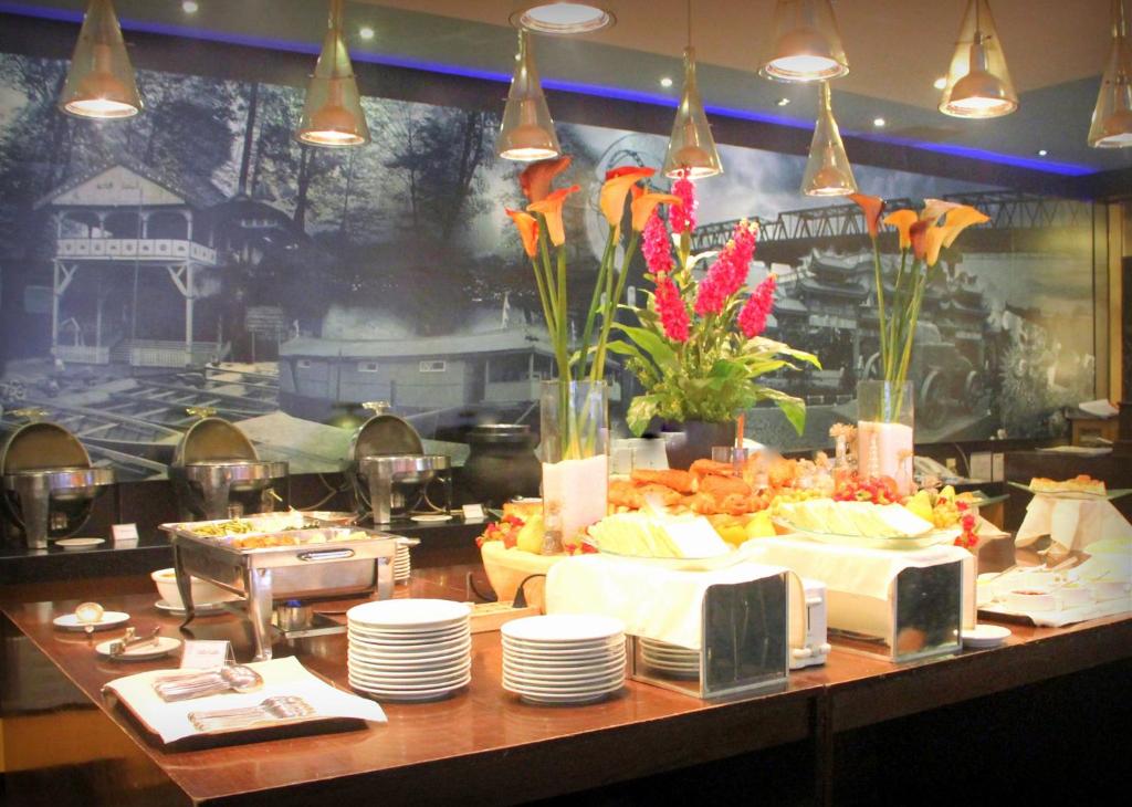 a buffet with plates and flowers on a table at Hotel Kini Pontianak in Pontianak