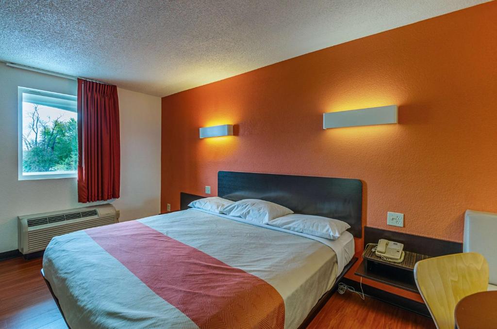 a bedroom with a large bed with an orange wall at Motel6 Winchester, VA in Winchester