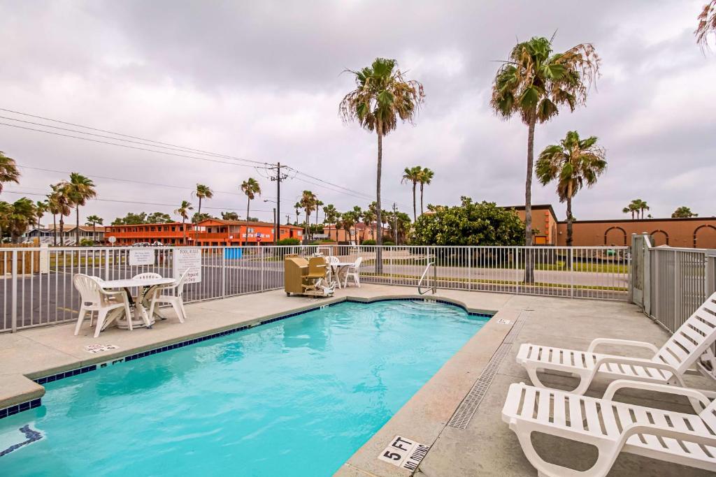 a swimming pool with chairs and a table and chairs at Ocean Inn South Padre Island in South Padre Island