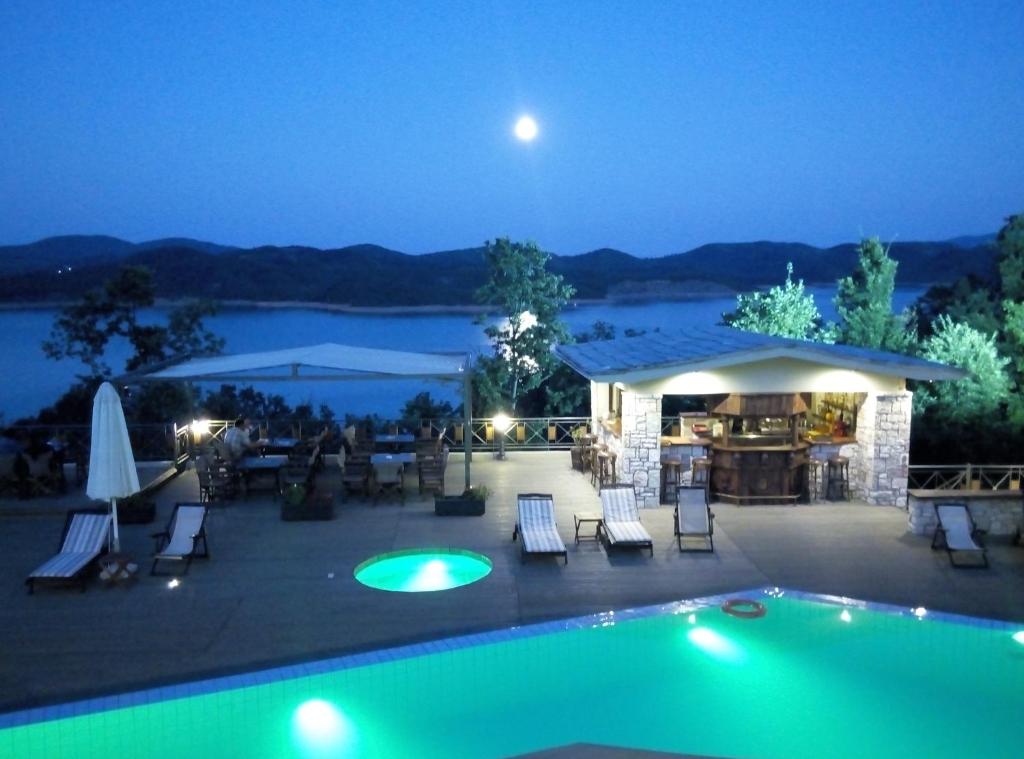 uma vista para uma piscina à noite em Naiades Hotel Resort & Conference em Neochori