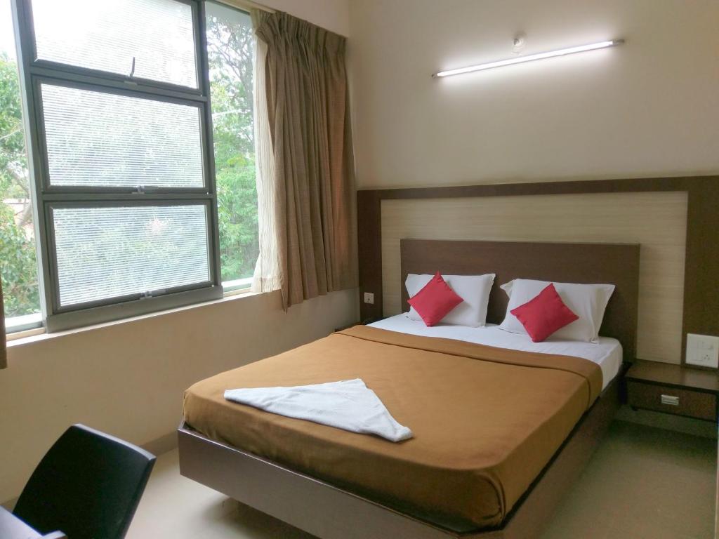 a bedroom with a bed with red pillows at Banyan Tree Comforts Mysore in Mysore