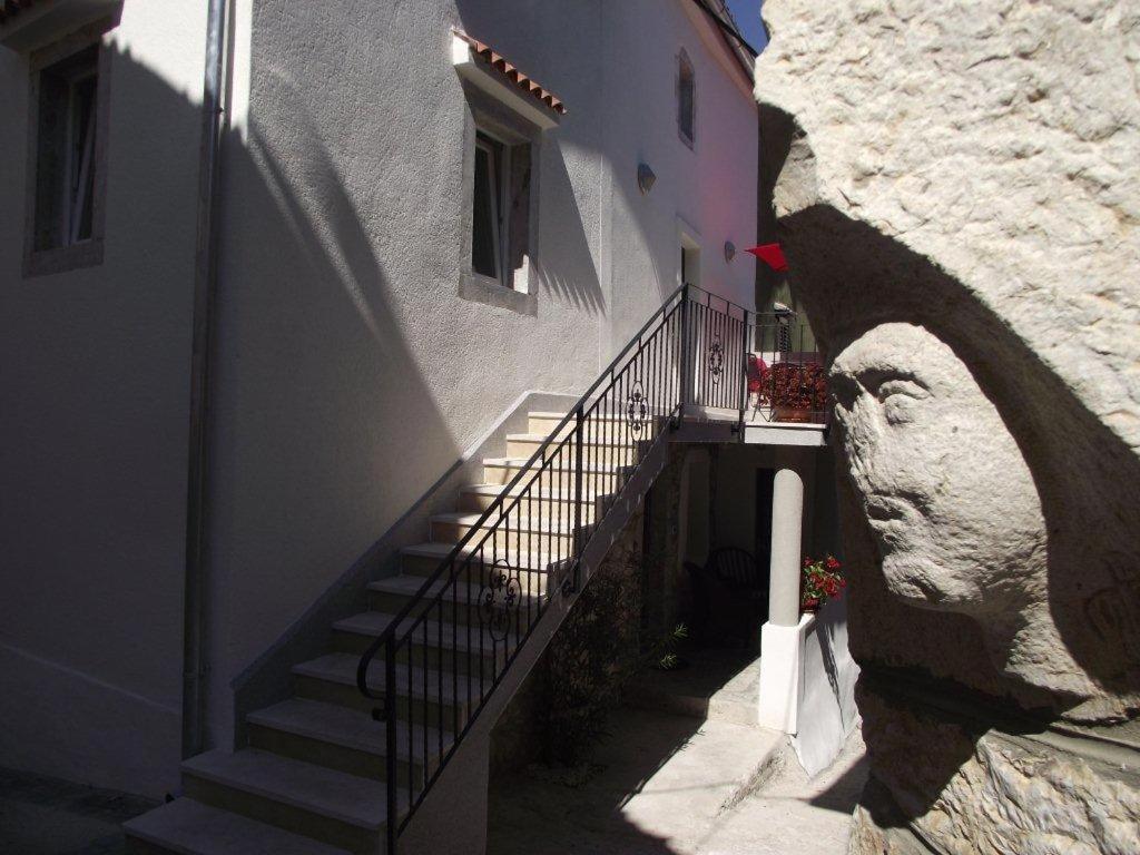 een trap naar een gebouw met een standbeeld van een hoofd bij Apartments Dobrinj in Dobrinj