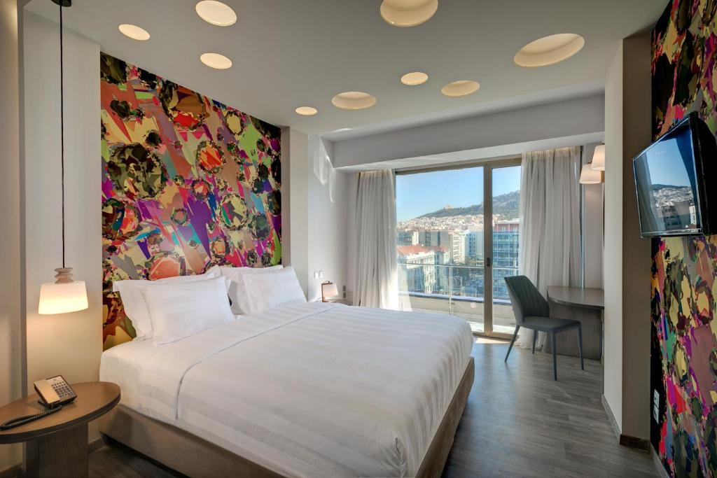 una camera da letto con un grande letto bianco e una grande finestra di Athens Tiare by Mage Hotels ad Atene