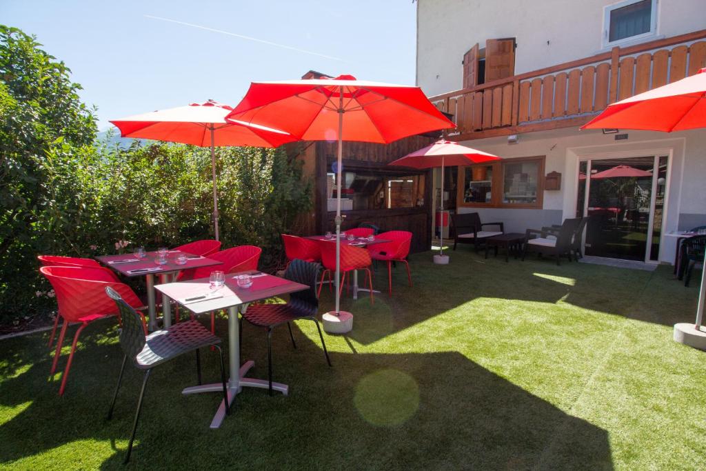 a patio with red tables and chairs and umbrellas at L auberge du basilico in Aime