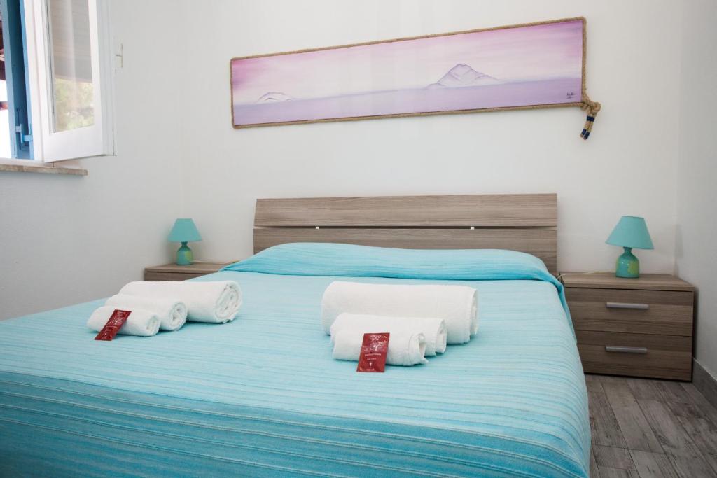 ein Schlafzimmer mit einem blauen Bett mit vier Kissen in der Unterkunft Titina Village Porto in Vulcano