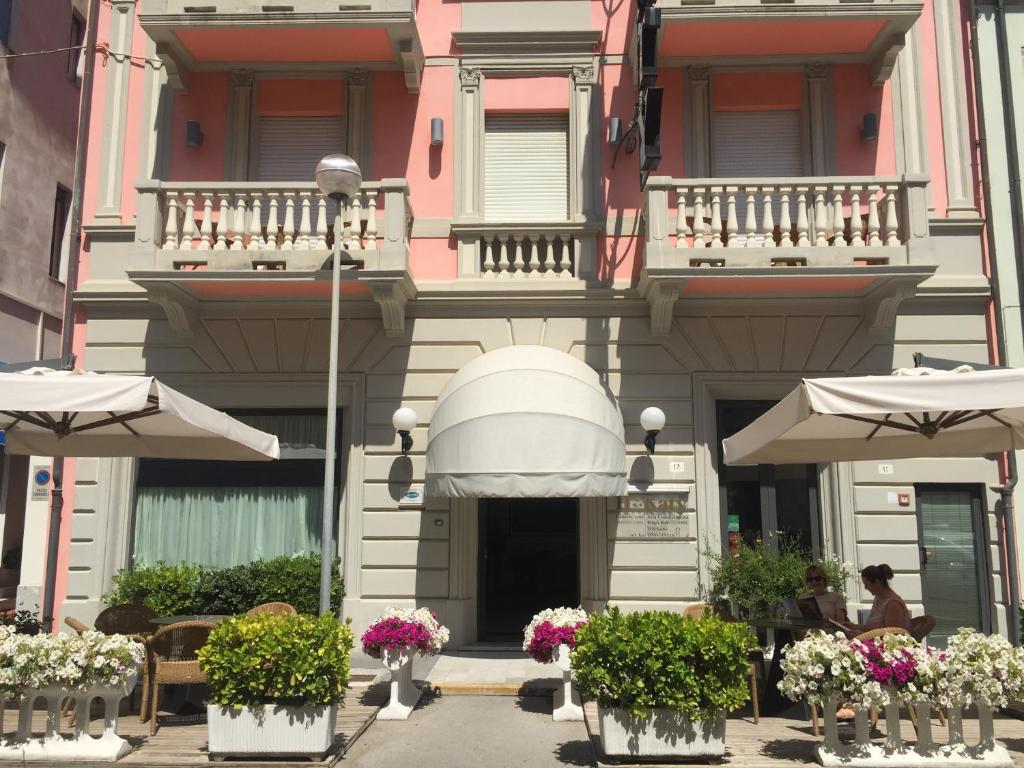 ein Gebäude mit Blumen und Sonnenschirmen davor in der Unterkunft Hotel Katy in Viareggio