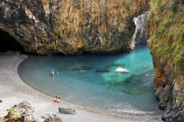 a group of people on a beach near a cave at Villa Crawford in San Nicola Arcella