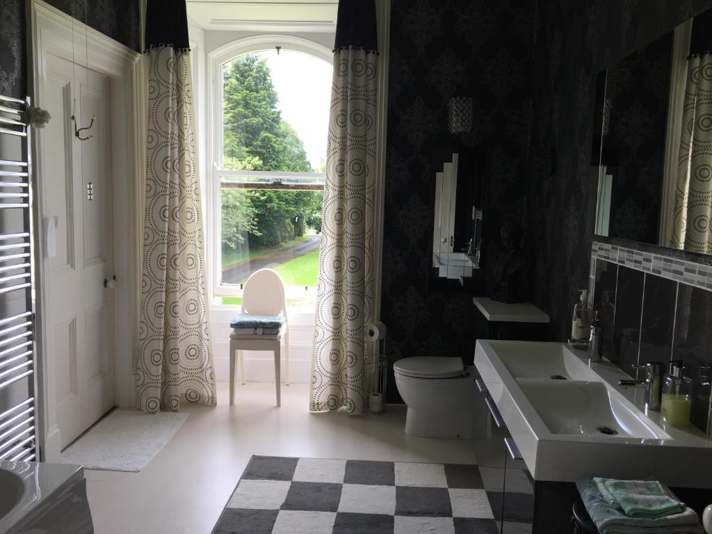 a bathroom with a sink and a toilet and a window at Gardenvale Manor House B&B in Stranocum