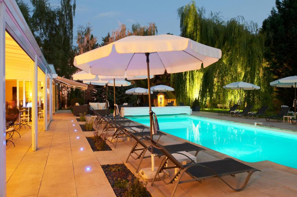 a pool with chairs and umbrellas next to a pool at Les Jardins D'Adalric in Obernai