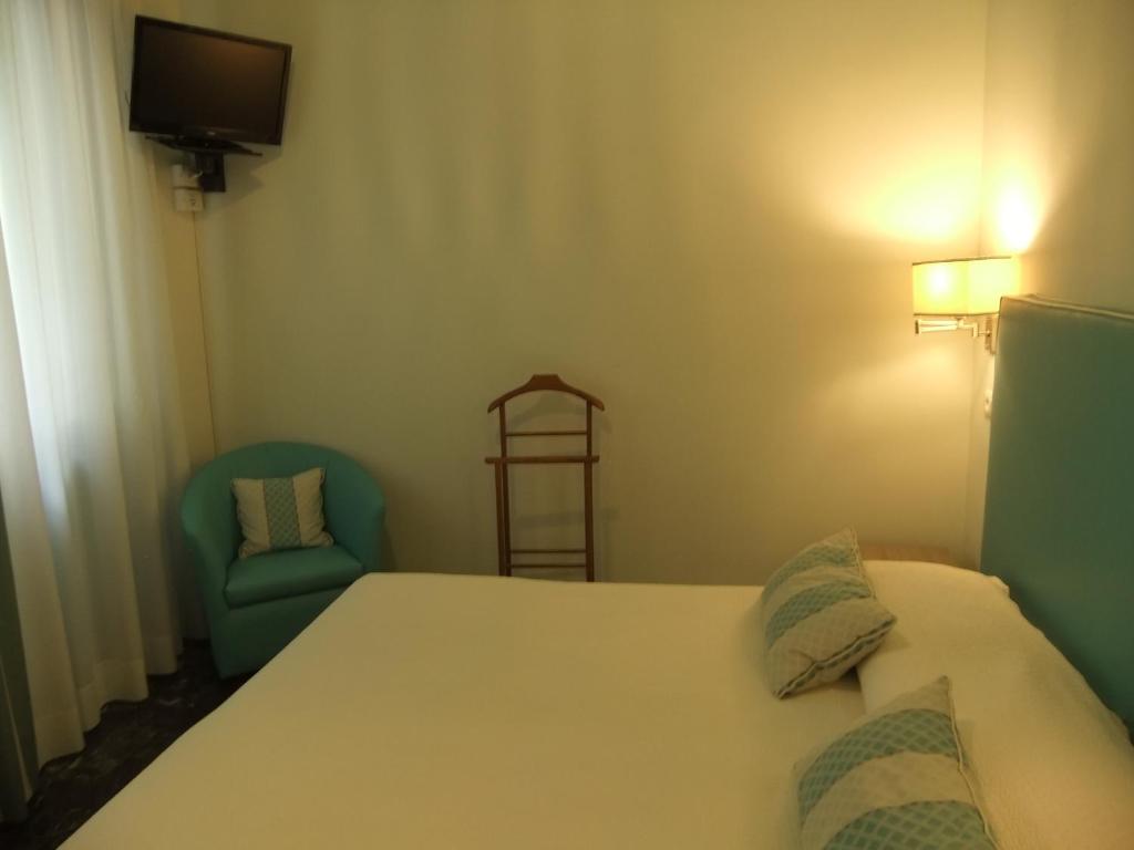 a bedroom with a bed and a chair and a television at Hotel Giulio Cesare in Cinquale