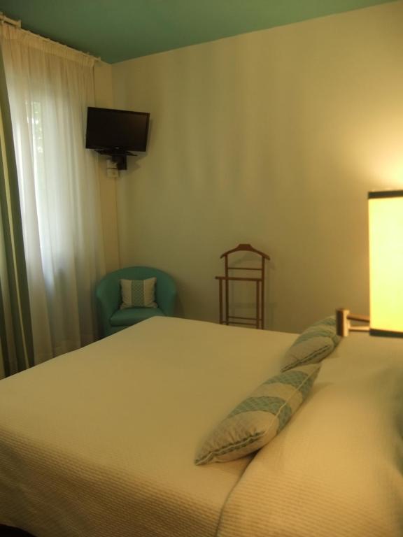 a bedroom with a bed and a chair and a television at Hotel Giulio Cesare in Cinquale