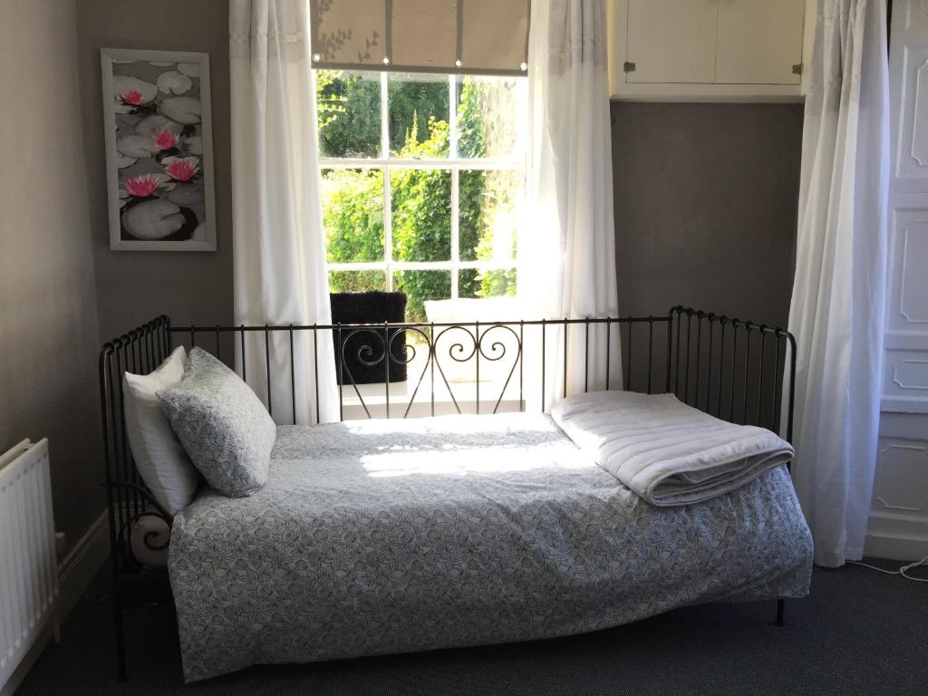 a small bed in a room with a window at Gardenvale Manor House B&B in Stranocum