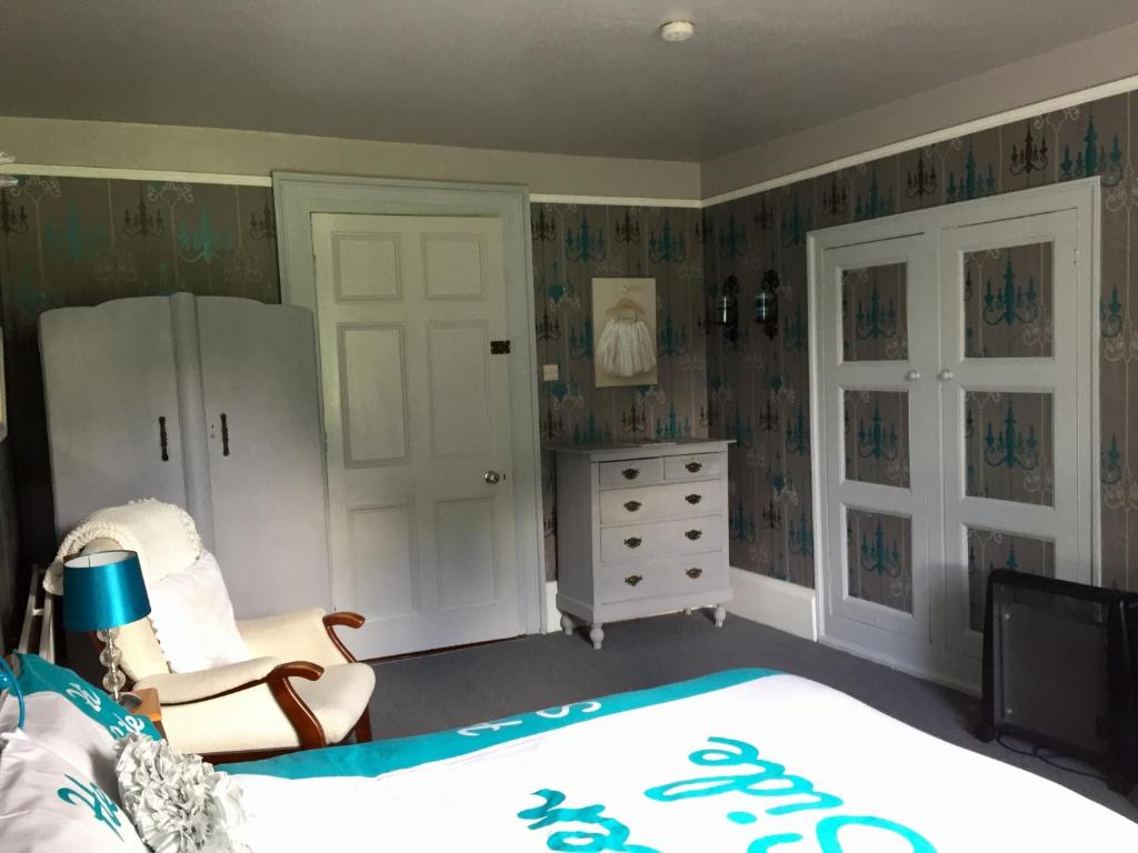 a bedroom with a bed and a chair and a dresser at Gardenvale Manor House B&B in Stranocum