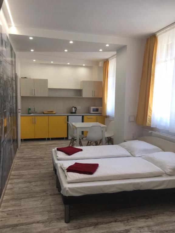 ein Schlafzimmer mit 2 Betten und eine Küche mit gelben Schränken in der Unterkunft Kálvin Vendégszobák in Debrecen