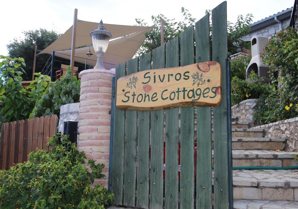 uma cerca com um sinal para uma loja em Sivros Stone Cottages em Sívros