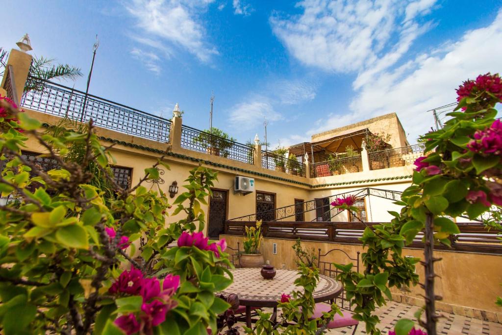 un edificio con un balcón con flores rosas en el primer plano en Riad 53 Fes - Luxury Oasis en Fez