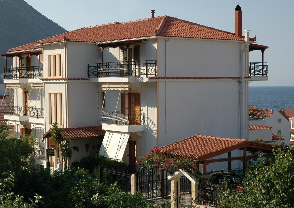 a large white building with balconies and the ocean at Makis Studios & Apartments in Póros Kefalonias