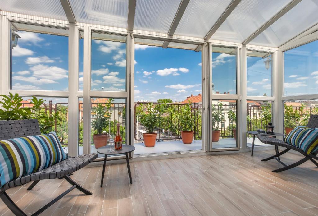 un gran salón acristalado con grandes ventanas y plantas en Terrace Apartments at City Park, en Budapest