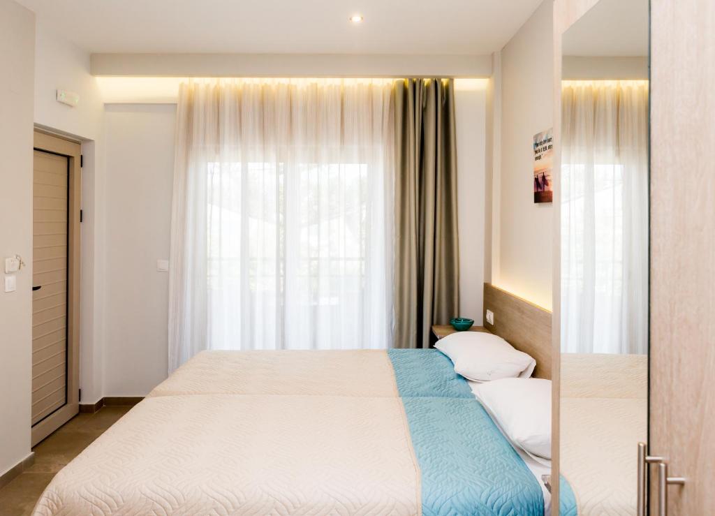 a bedroom with a large bed and a window at Lola's Hotel in Platanias