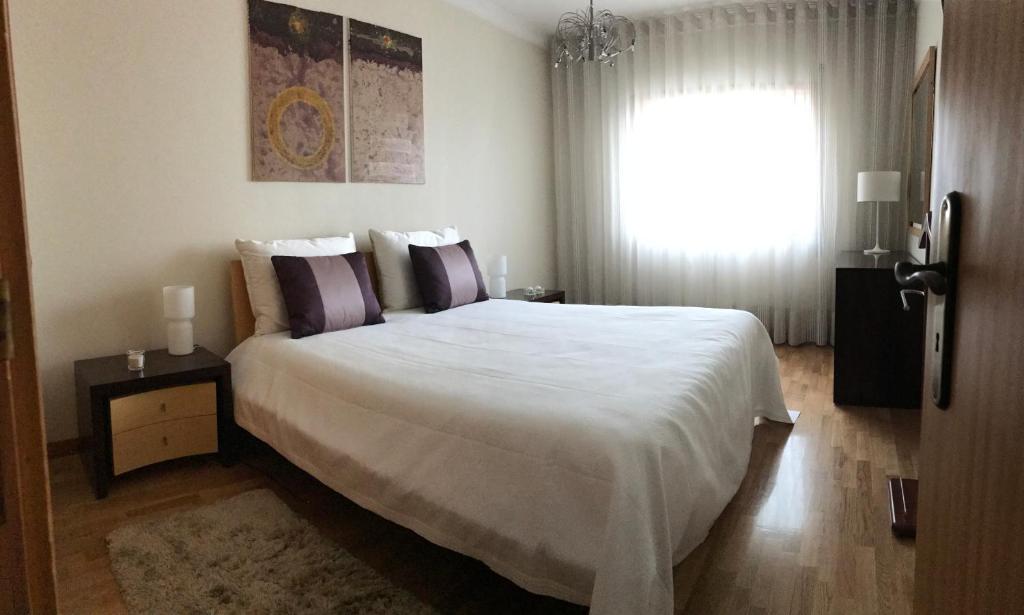 a bedroom with a large white bed and a window at Varandas da Sandia in Vila Praia de Âncora