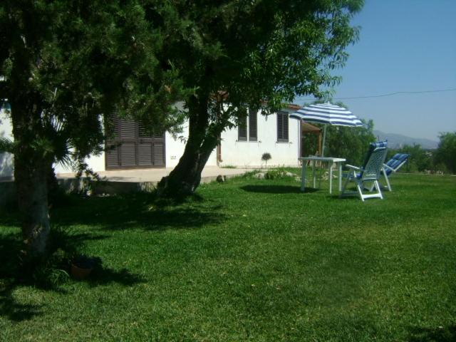 um quintal com duas cadeiras, uma mesa e um guarda-sol em Villa Flavia em Noto Marina
