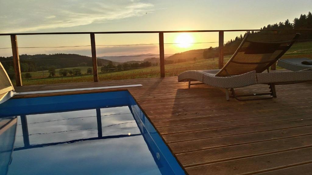 a deck with a swimming pool and a hammock and the sunset at Vila Pasečná - Lipno in Přední Výtoň