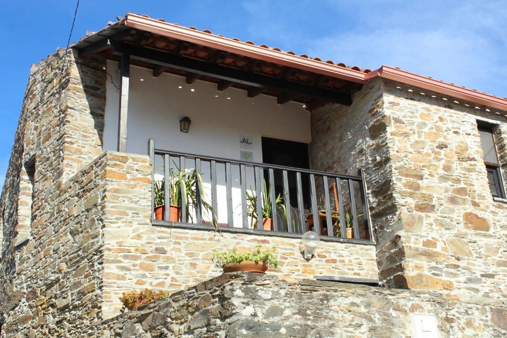 a stone building with a balcony with plants on it at Casas de Pedra in Proença-a-Nova