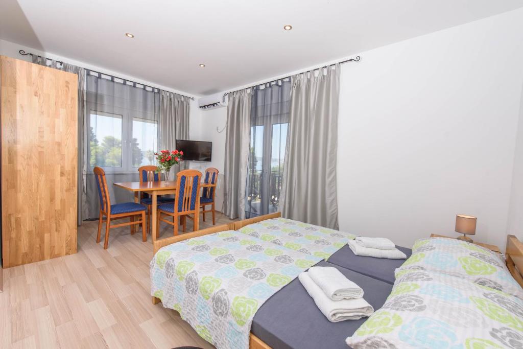 a bedroom with two beds and a table with chairs at Luxury Rooms Ivana in Kaštela
