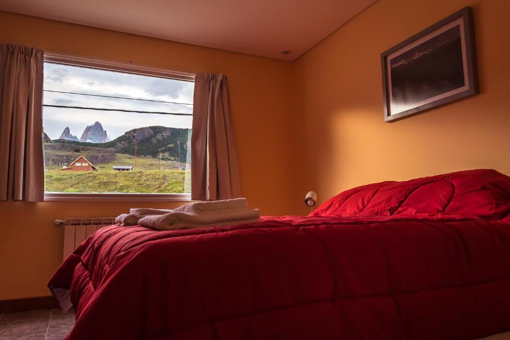 a bedroom with a red bed and a window at Apart Guillaumet in El Chalten