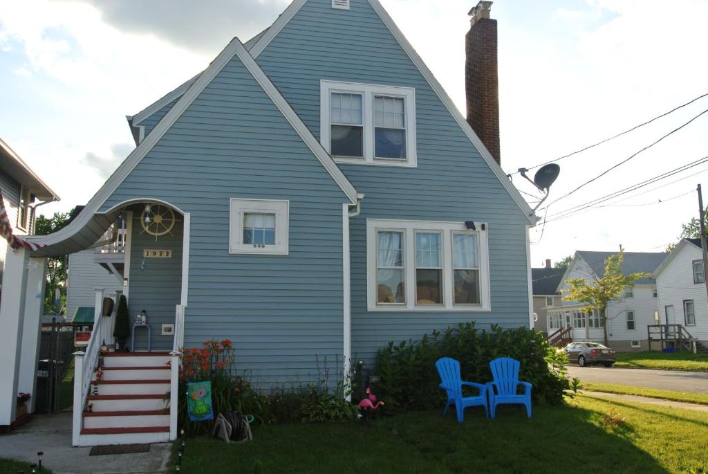 a blue house with two blue chairs in the yard at Cozy Cape Cod Vacation House in Two Rivers in Two Rivers