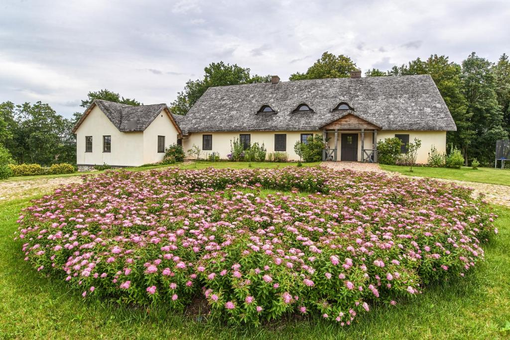 a house with a large circle of flowers in front of it at Dworek Szejpiszki z Prywatnym Półwyspem in Romanowce