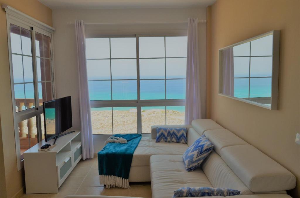 een woonkamer met een bank en een groot raam bij Apartamento Vista Esmeralda en PLAYA PARAISO in Costa Calma