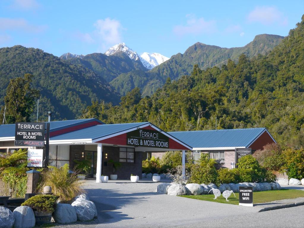 um edifício com montanhas ao fundo em The Terrace em Franz Josef