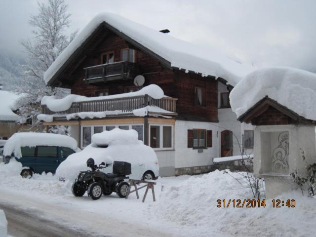 a snow covered house with a motorcycle parked in the snow at Haus Mittagspitze in Mellau