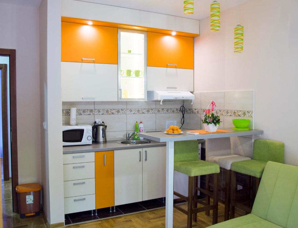 eine Küche mit weißen Schränken und grünen Akzenten in der Unterkunft Apartman Lena in Vrnjačka Banja