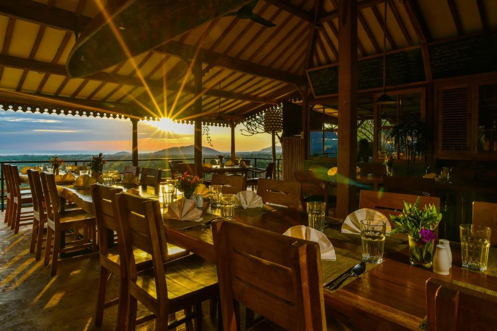 a restaurant with tables and chairs with the sunset in the background at Sumberkima Hill 1 in Pemuteran
